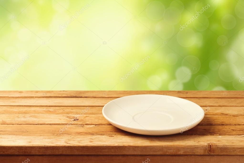 Empty plate on wooden table over bokeh background Stock Photo by