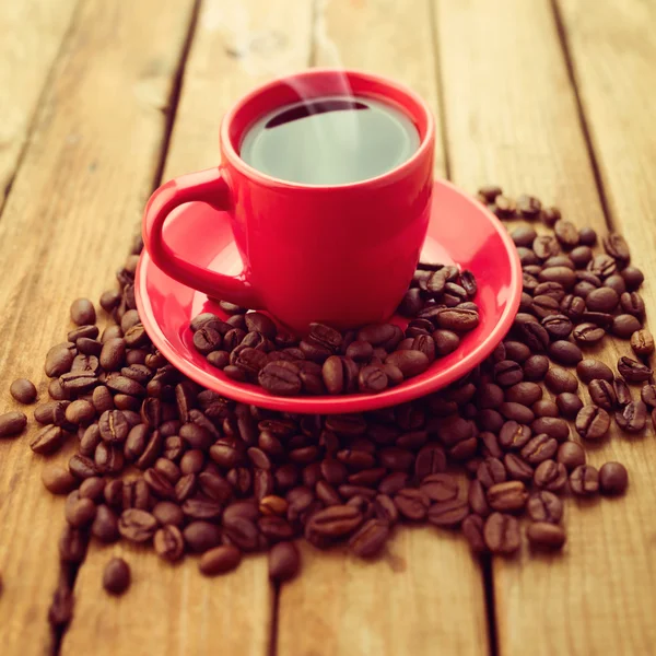 Red coffee cup with coffee beans on wooden background — Stock Photo, Image