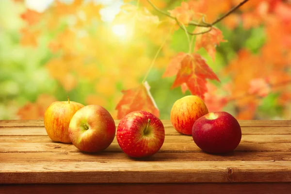 Яблоки на деревянном столе на осеннем фоне боке — стоковое фото