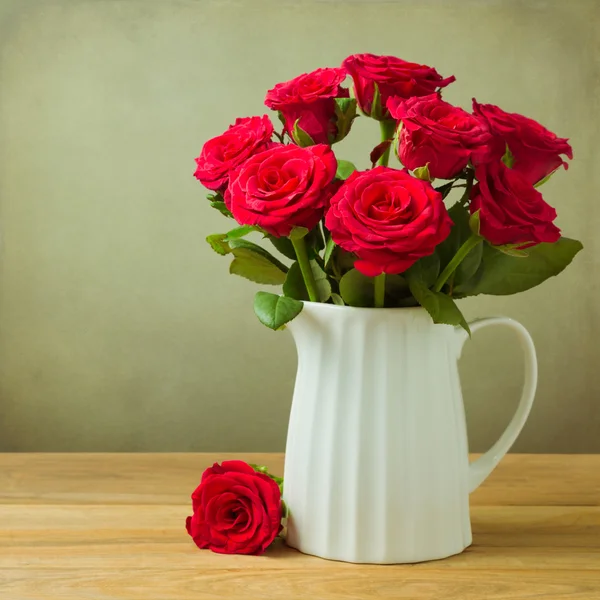 Bouquet de fleurs roses en cruche sur table en bois — Photo