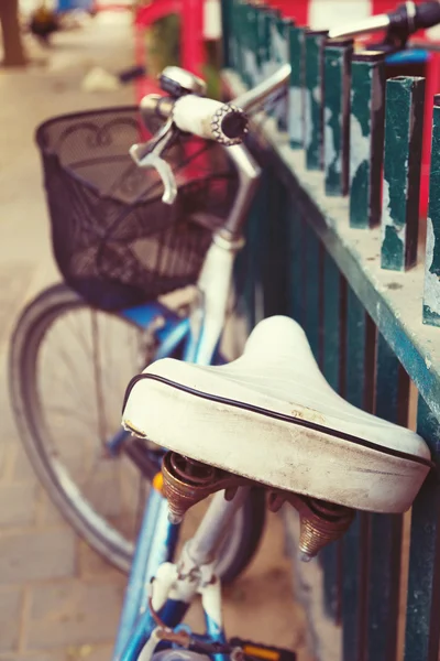 Oude fiets in de buurt van hek op stedelijke straat — Stockfoto