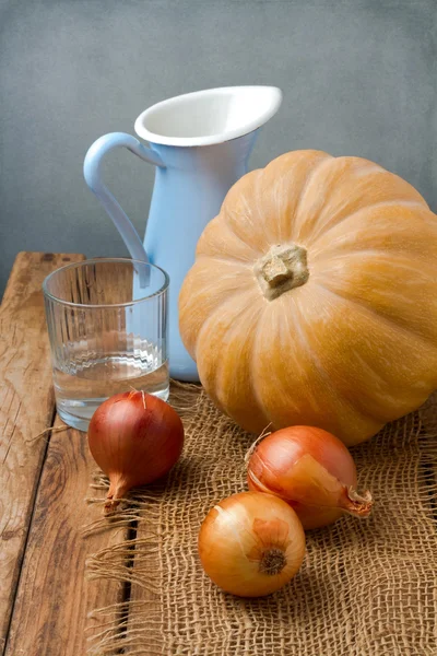 Still life with pumpkin and onions on wooden table — Stock Photo, Image