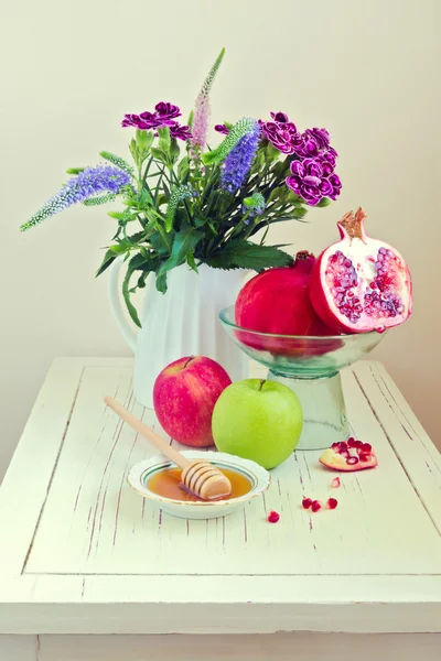 Natura morta con mela, miele, melograno e fiori — Foto Stock