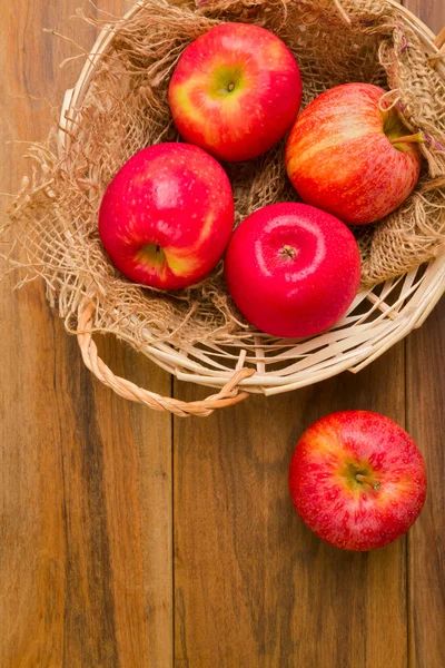 Frische rote Äpfel im Korb vor Holzhintergrund — Stockfoto