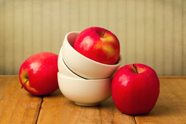 Manzana roja en la pila de cuencos en la mesa de madera — Foto de Stock