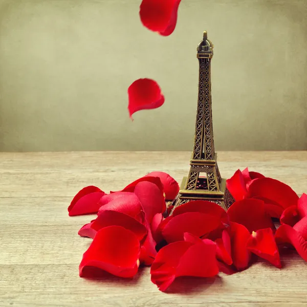 Pequeña torre Eiffel con pétalos de rosas — Foto de Stock