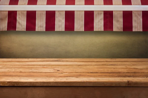 Dřevěný stůl s pozadím markýza — Stock fotografie