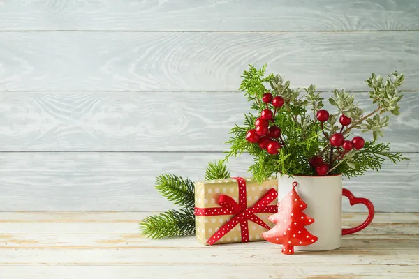 咖啡杯中的圣诞树分枝和木制桌子背景上的礼品盒 — 图库照片