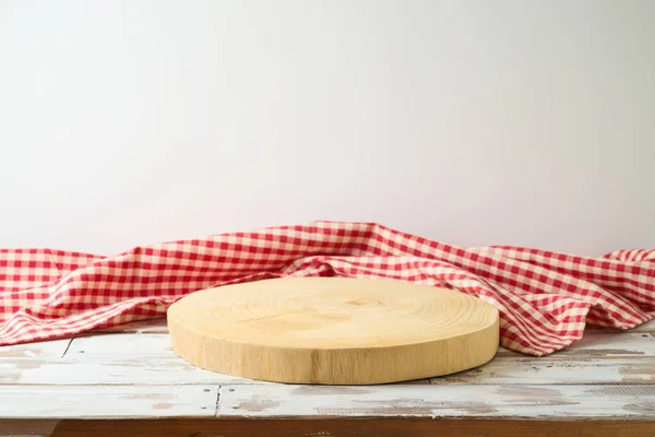 Empty wooden log  with red checked tablecloth on rustic table over white wall  background.  Kitchen mock up for design and product display.