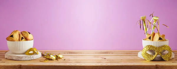 在紫色背景上的木制桌子上夹着哈曼曲奇饼和狂欢节面具的犹太假日普利姆概念 — 图库照片