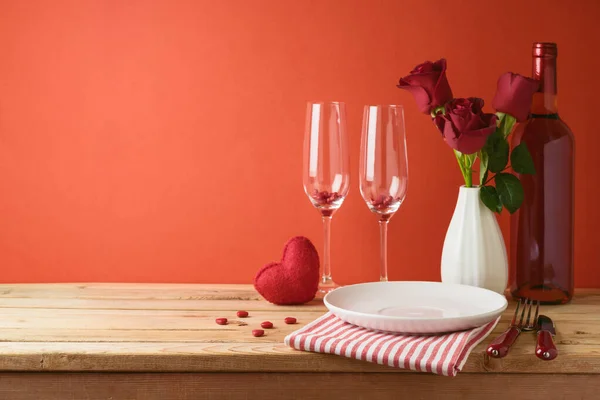バレンタインデーロマンチックなディナーのコンセプト ワインボトルと赤い背景にバラの花を持つ木製のテーブル — ストック写真