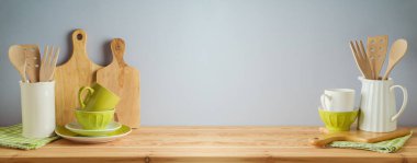 Mutfak gereçleri ve yeşil bulaşık takımları gri arka plandaki ahşap masada. Bahar ve Paskalya tatili tasarım için hazırlanıyor