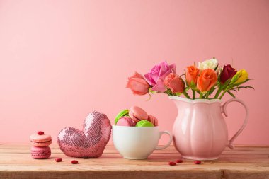 Mutlu Anneler Günü konsepti. Kurabiyeler, kurabiyeler ve ahşap masa üzerindeki gül çiçekleri pembe arka plan.