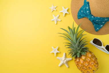 Yaz tatili kavramı. Sarı arka planda ananas ve yaz şapkalı düz kompozisyon
