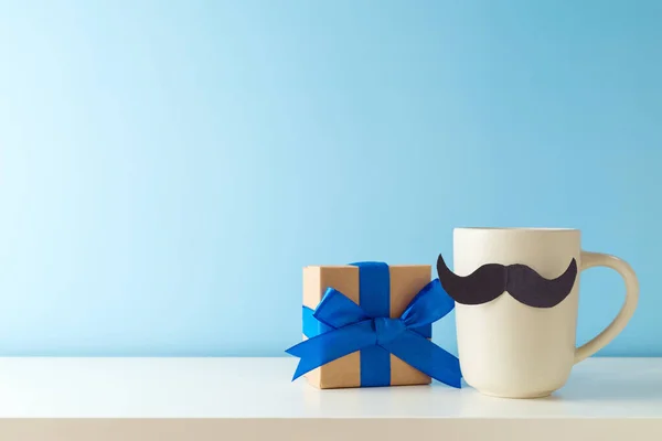 青い背景の上に白いテーブルの上に口ひげとギフトボックスとコーヒーカップ 幸せな父の日の挨拶カード — ストック写真