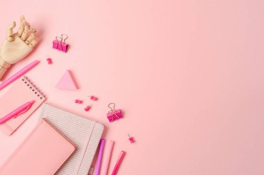 Feminine pink desk with notebook and stationery. Background for back to school concept. Top view, flat lay