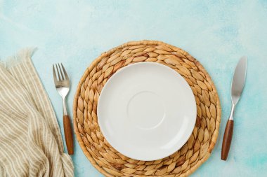 Modern table setting with empty plate, tablecloth and silverware. Mock up background for display. Top view, flat lay