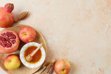 Jewish holiday Rosh Hashanah concept with honey, apple and pomegranate on stone background. Top view, flat lay