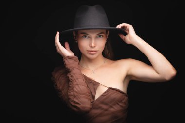 Siyah arka planda siyah şapkalı güzel bir kızın moda stüdyo portresi. Alçak tuş.