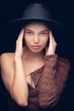 Siyah arka planda siyah şapkalı güzel bir kızın moda stüdyo portresi. Alçak tuş.