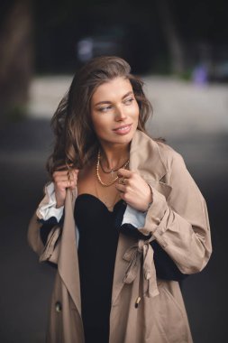 Şehir sokaklarında şık bir yağmurluk giyen beyaz beyaz beyaz kız.