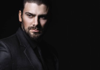 Sert erkek portresi. Klasik siyah takım elbiseli adam. Yarı yüz ışıkta.