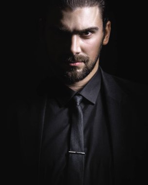 Sert erkek portresi. Klasik siyah takım elbiseli adam. Yarı yüz ışıkta.