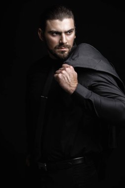 Siyah ceketli, gömlekli ve siyah kravatlı beyaz bir adam alnının altından dışarı bakıyor. Sert erkek portresi. Klasik siyah takım elbiseli adam..