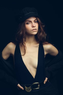 Siyah şapkalı ve siyah arka planda seksi bluzu olan güzel bir modelin moda stüdyo portresi. Alçak tuş.
