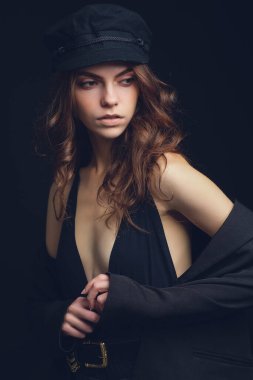 Siyah şapkalı ve siyah arka planda seksi bluzu olan güzel bir modelin moda stüdyo portresi. Alçak tuş.