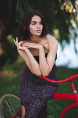 Bisikletli kız. Parkta kırmızı bisikletli beyaz beyaz, çekici bir kız.