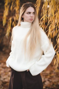 Sonbahar renklerinde beyaz süveter giyen çekici bir sarışın.