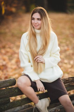 Çekici bir sarışının harika bir gülümsemesi olan portresi. Beyaz kazaklı kız.