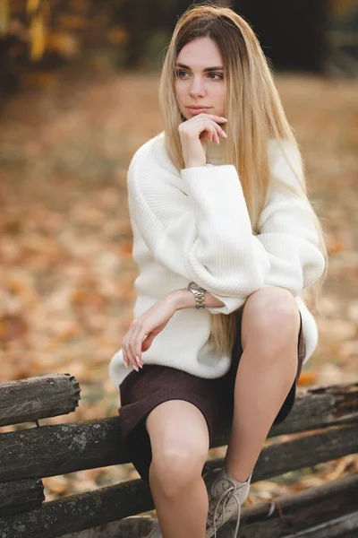 Sonbahar renklerinde beyaz süveter giyen çekici bir sarışın.