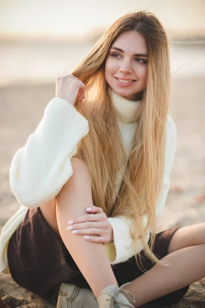 豪華な笑顔で魅力的なブロンドの肖像画 白いセーターを着た女の子が川岸でリラックスしている — ストック写真