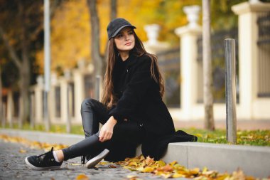 Autumn portrait of an attractive girl in a baseball cap. Autumn shades. Stylish girl