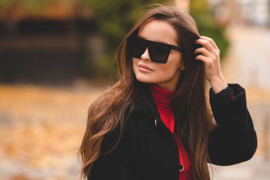 Ceketli ve şık gözlüklü çekici bir genç kızın moda portresi. Ilık sonbahar gölgeleri.