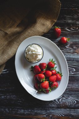 Kremalı çilek. Yemek fotoğrafçılığı. Koyu ahşap arka planda iştah açıcı çilekler.