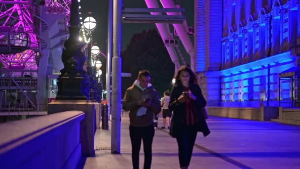 ロンドン 2021年9月14日 ロンドン アイとカラフルに照らされた郡庁舎の間をスマートフォンで歩く人々 — ストック動画