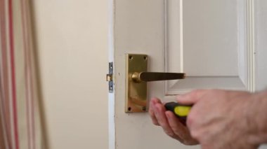 Eski beyaz bir iç kapının kapı kolunu çıkarmak için tornavida kullanmış.