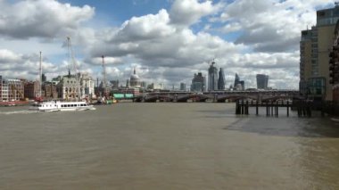 Londra, İngiltere 'nin finans bölgesinin ufuk çizgisi ile Blackfriars Köprüsü' ne yaklaşan gezi teknesi. Yoğun bulutlu gökyüzü ile geniş açıyla kilitlendi..