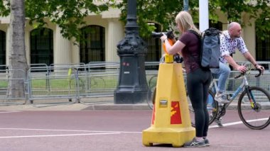 LONDON - 18 Mayıs 2022: Kadın fotoğrafçı The Mall boyunca trafiğin ortasında trafik konisine kamera yerleştirdi