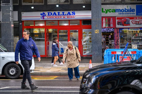 LONDON - May 20, 2022: People crossing busy London street between taxis