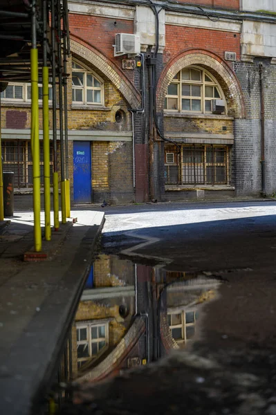 LONDON - May 20, 2022: Old brick railway archway buildings at Waterloo reflected in puddle on road