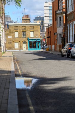 LONDON - May 20, 2022: Old chimneys on brick building and reflected in puddle on the road