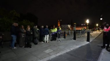 15 Eylül 2022 'de, gece güvenlik noktasından geçen insanların Kraliçe Elizabeth' i yerde yatarken görmek için zaman çizelgesi. Arka planda Parlamento Binası