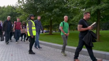 14 Eylül 2022 'de bir kahya, Jubilee Park' taki kuyrukta bekleyenleri Kraliçe 'yi yerde yatarken görmeleri için yönlendirir.