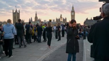 14 Eylül 2022 'de Westminster Köprüsü' ndeki TV haber ekipleri Kraliçe Elizabeth II 'yi görmek için kuyrukta bekliyorlar. Parlamento binaları gün batımında arka planda
