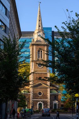 LONDON - 2 Kasım 2020: Aldgate 'siz St Botolph ve arka planında modern cam ofis binaları olan Kutsal Üçlemeci Minories Kilisesi