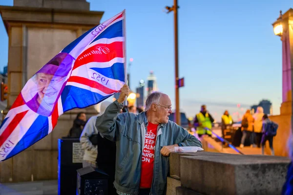 stock image London - September 17, 2022: Man holds Union Jack flag with Queen's face on it in early evening light